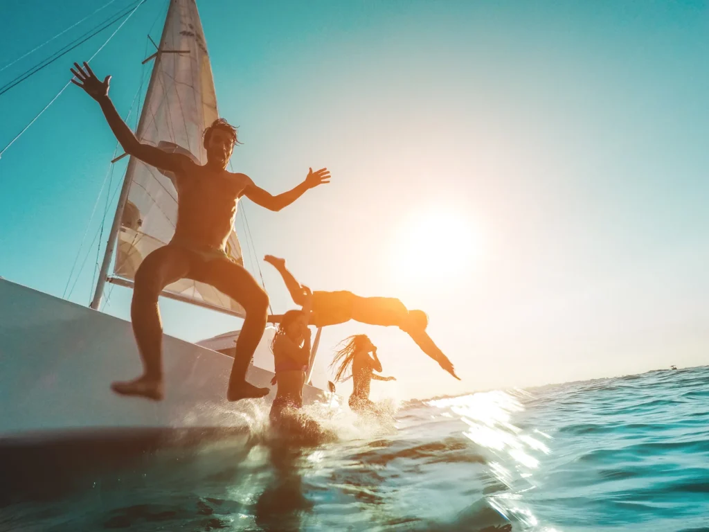 Friends jumping into the sea from a sailboat