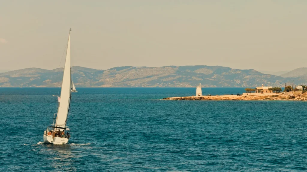 Sailboat passing the Aegina lighthouse at sunset