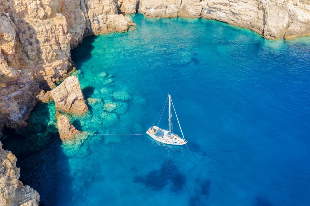 Sailboat anchored in a turquoise cove in the Aegean