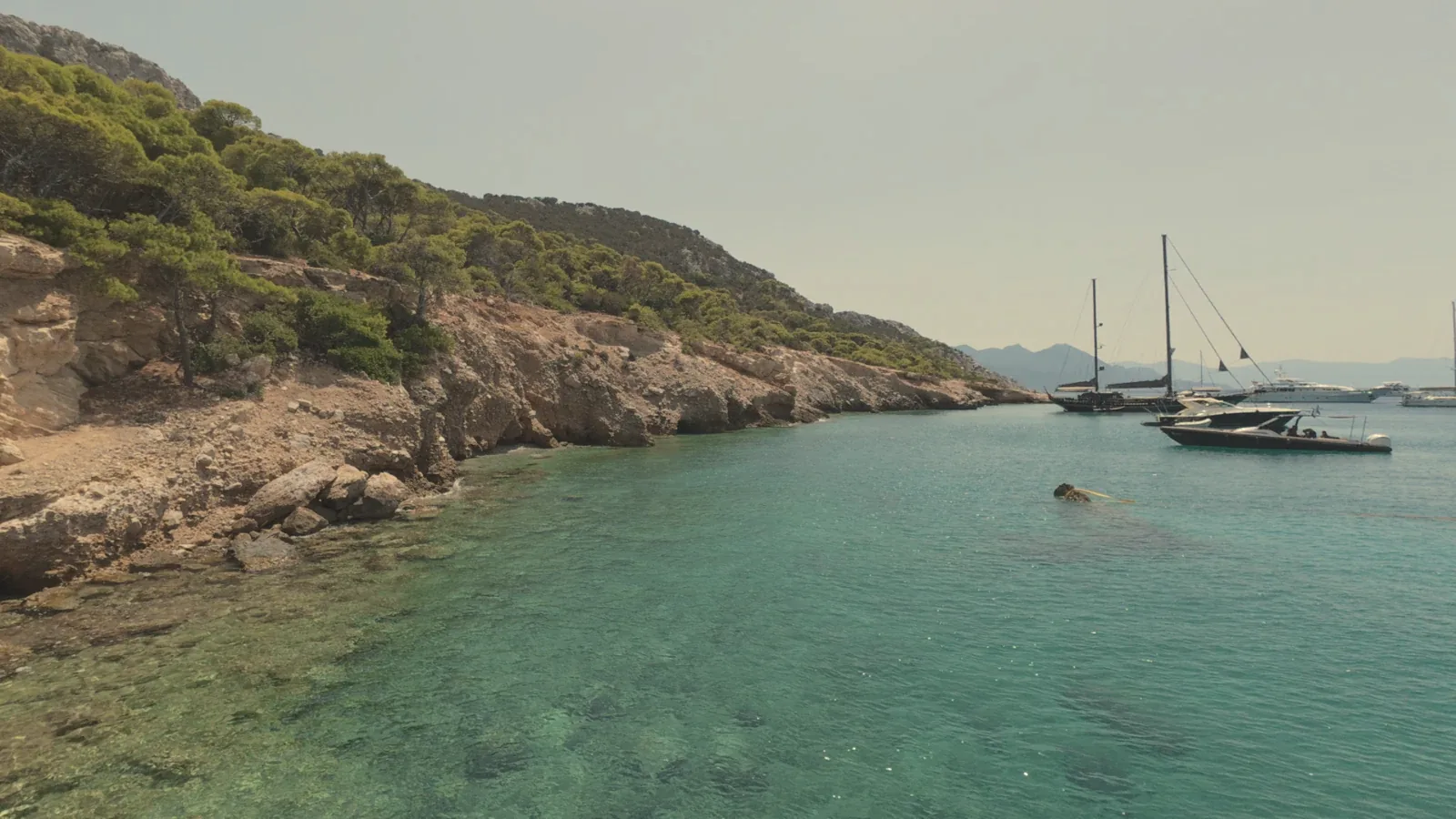Yachts anchored in a quiet bay with clear water in the Saronic Gulf