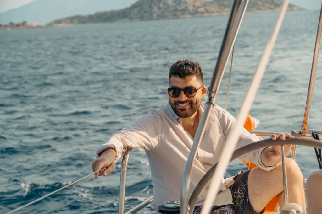 Smiling guest at the wheel of a sailing yacht in Greece