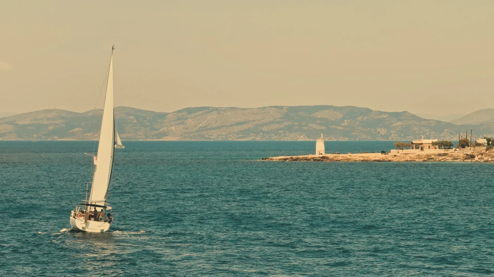 Sailboat passing the Aegina lighthouse at sunset