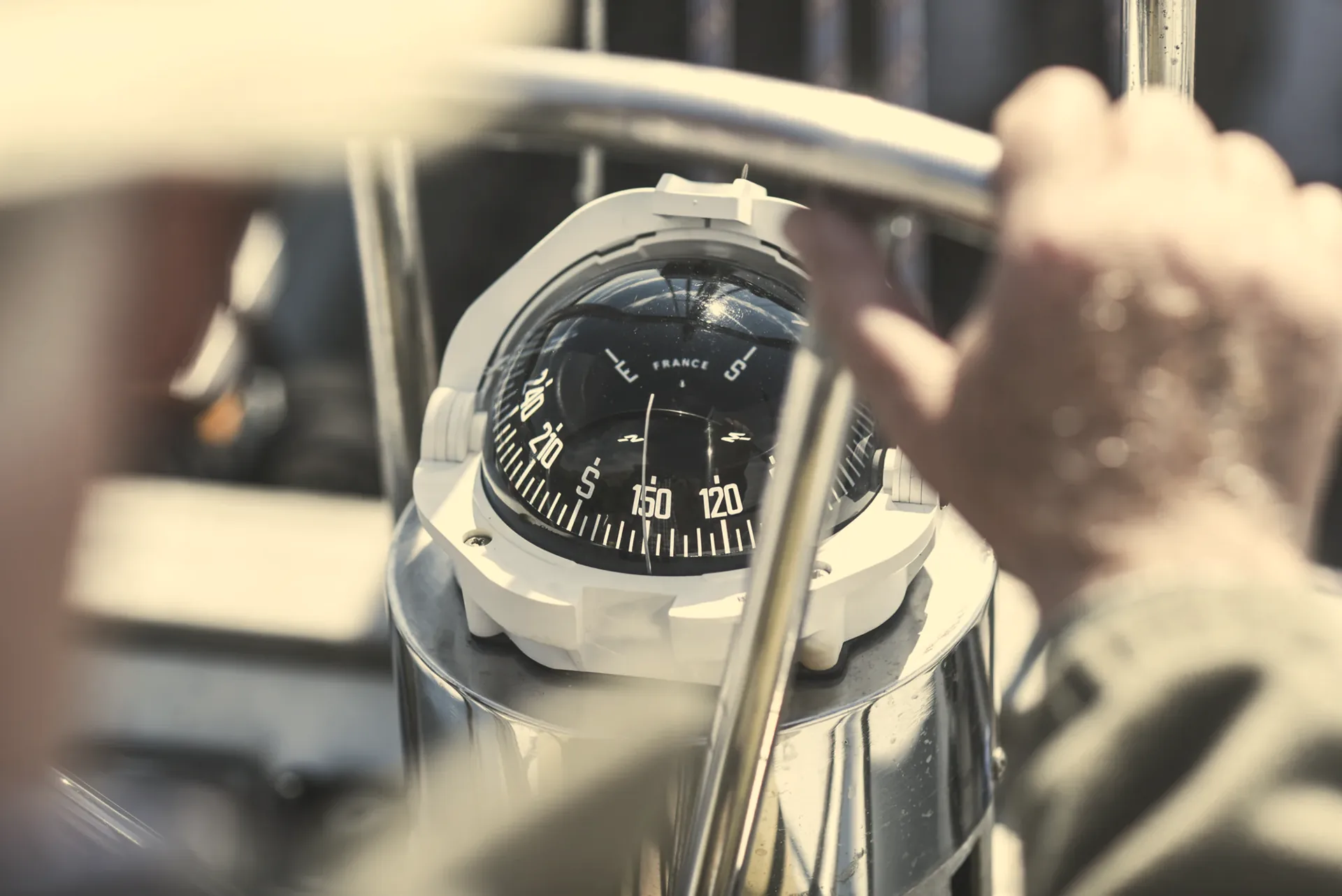 Hand on a yacht wheel with the compass